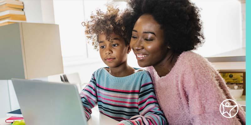 A mother is looking at a laptop with her daughter