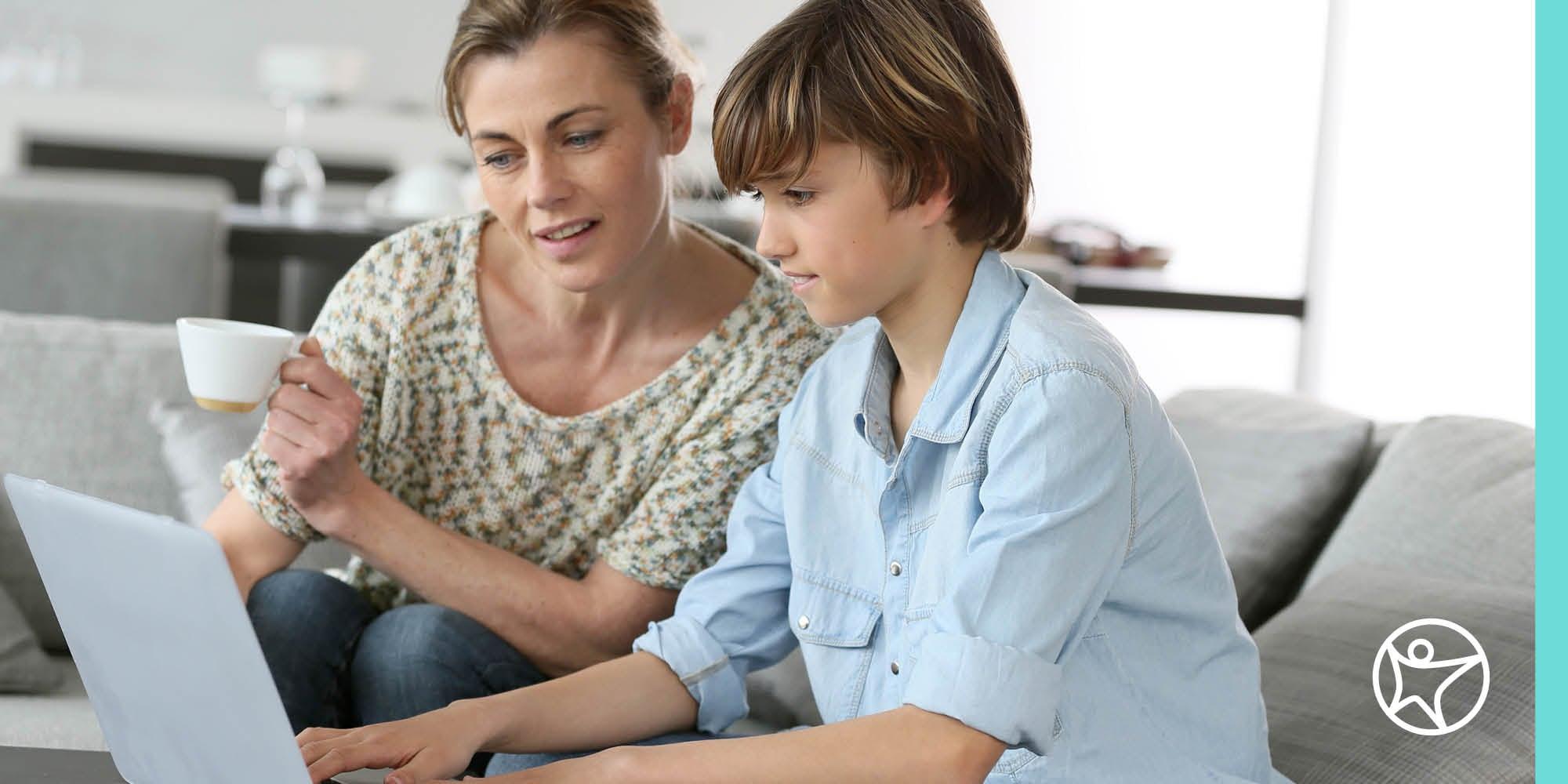 A mother is looking at a laptop with her son